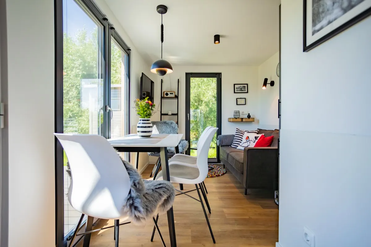 Lichtdurchfluteter Wohnbereich eines TMF Tiny Houses mit Essplatz und Sofa